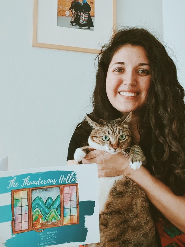 The Thunderous Hello: Raquel Cruz, Illustrator with the book and her cat.