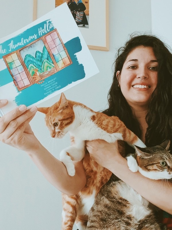 The Thunderous Hello: Raquel Cruz, Illustrator with the book and her cat.